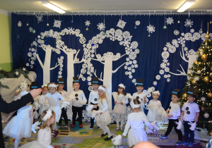 Dzieci z grupy Żabki, przebrane za śnieżynki i bałwanki, tańczą.